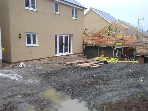 A garden before work begins with a pile of topsoil and large puddle of water