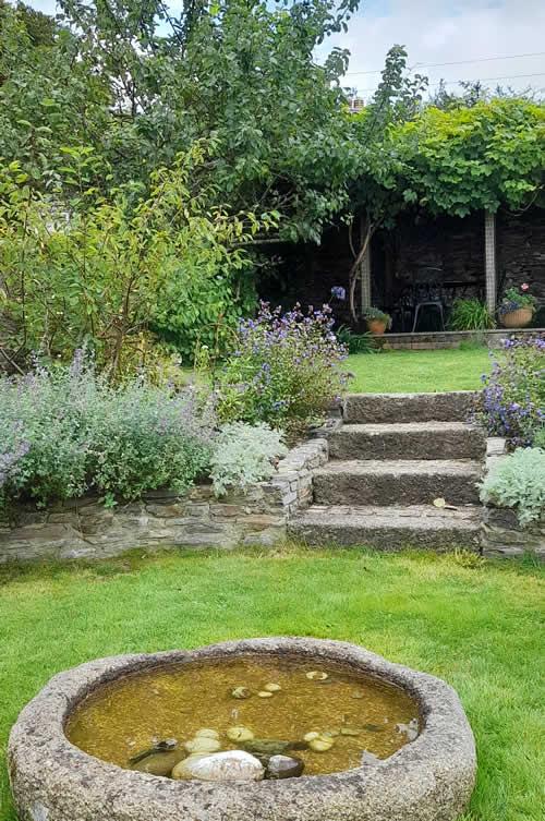 A relandscaped garden in Whitchurch with granite steps and trough 