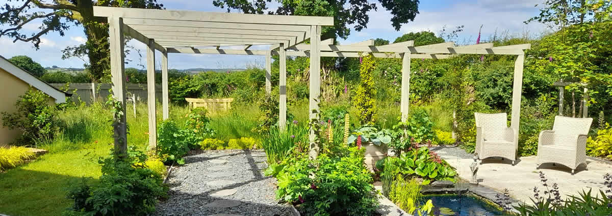 A landscaped garden with seating area, ponds, pergolas and planted beds in a new-build garden